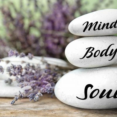 Composition of lavender flowers and zen stones with words Mind, Body, Soul on table against blurred background. Space for text